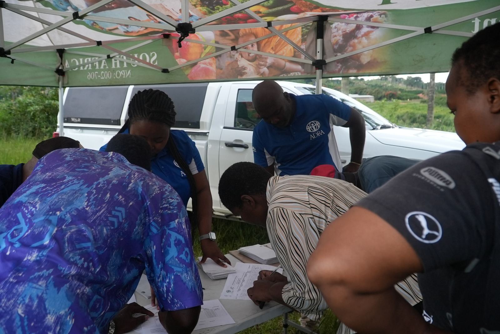 Community members and ADRA staff at a gazebo registration point